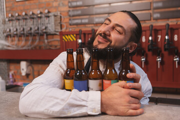 Happy bartender smiling with eyes closed hugging beer bottles