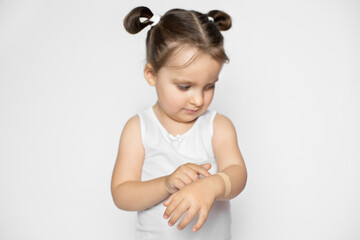 A little cute 3 years old girl with blonde hair demonstrating how to apply adhesive plaster bandage on wound on her arm. Horizontal shot on isolated white background