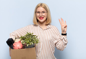 blonde woman smiling and looking friendly, showing number four or fourth with hand forward,...
