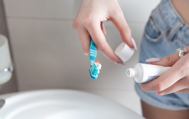 Young woman holding toothbrush before brushing teeth.