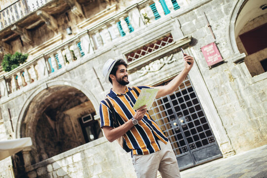 Happy tourist with backpack is making travel across city uses a map for orientation.