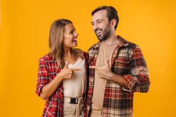 Nice joyful couple smiling and pointing fingers at each other