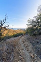 a female tourist walks along a mountain trail, at sunset, a panorama of a mountain range on the horizon .vertical photo