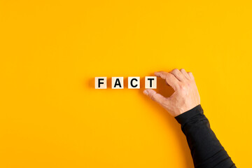Male hand placing the wooden cubes with the word fact - obrazy, fototapety, plakaty
