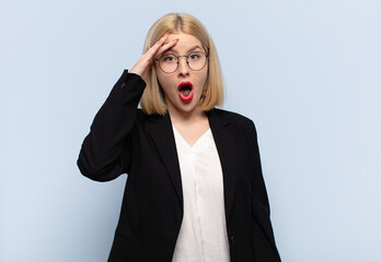 blonde woman looking happy, astonished and surprised, smiling and realizing amazing and incredible...