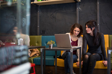 amiche si divertono a chiacchierare e scherzare in  un locale sedute nei divanetti di fronte al tavolino