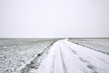 A snowy country road, dangerous and slippery during winter snowfall.