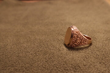 Mens gold signet ring on a beige background.