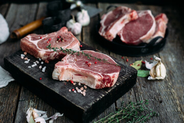 Raw pork steak on the bone on a wooden table. Cooking meat