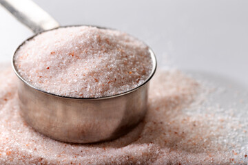 Powder Himalayan pink salt in measuring cup. Food background. Top view.