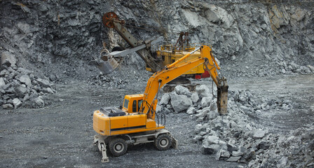 Hydraulic hammer and mining excavator in the limestone quarry, panorama.