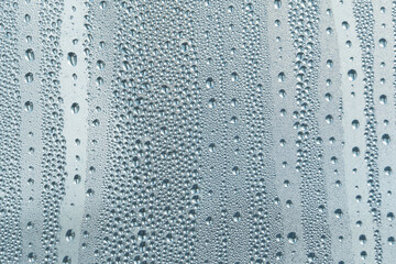 A small raindrop rests on the glass after rain. Raindrops On The Glass. Raindrops on the window. Blue tone. Abstract background.