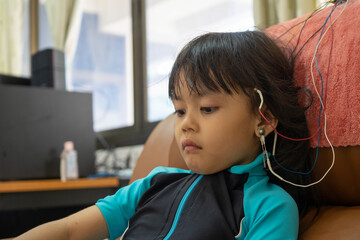 A little girl is wearing a hearing aid and is doing a neurofeedback exam. Making EEG electrodes.