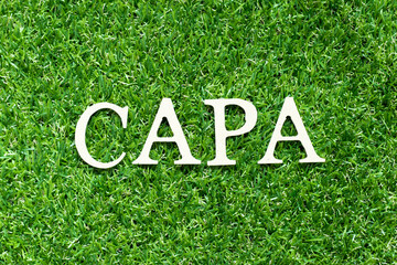 Alphabet letter in word CAPA (abbreviation of corrective action and preventive action) on green grass background