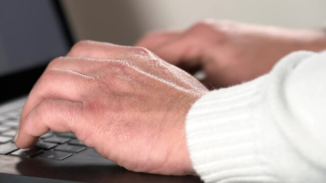 Old man hands typing over laptop keyboard