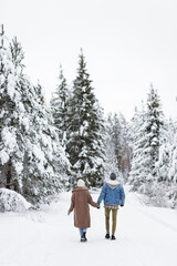 Fototapeta na wymiar love, happiness and relationship concept - back view of couple walking in winter forest