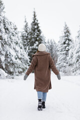 Back view of woman walking in winter forest