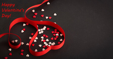 Valentines day concept with red hearts and red ribbon on black background, top view