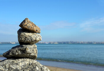 Fototapeta na wymiar stones stand one on the other on the seashore selective focus of the blurred background of the sea and blue sky