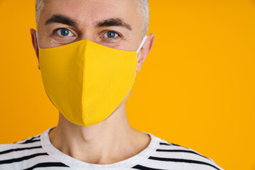 Joyful handsome man in protective mask looking at camera