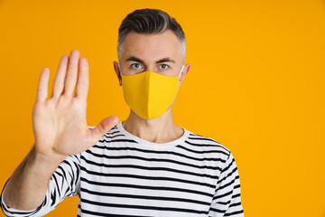 Confident handsome man in protective mask showing stop gesture