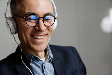 Cheerful grey man in headphones smiling while having break