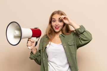 blonde woman looking happy, astonished and surprised, smiling and realizing amazing and incredible...