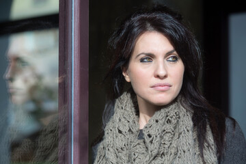 Ritratto di bellissima ragazza mora con gli occhi verdi che guarda in lontananza, sullo sfondo un...