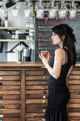 ragazza mora con gli occhi verdi ed espressione serie prende qualcosa da bere  in un bar 