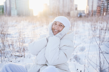 Obraz premium Happy elderly senior mature woman in white warm outwear playing with snow in sunny winter outdoors. Retired healthy people holiday vacation winter activities, active lifestyle concept.