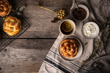 Breakfast with knot buns, orange jam, cream cheese and  black tea with lemon on wooden table. 