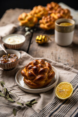 Breakfast with knot buns, orange jam, cream cheese and  black tea with lemon on wooden table. 