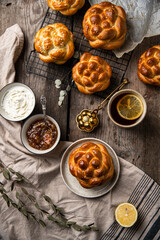 Breakfast with knot buns, orange jam, cream cheese and  black tea with lemon on wooden table. 