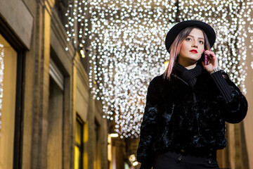 Bella ragazza con i capelli castani dipinti di viola con un cappotto e  un cappello nero  và in...