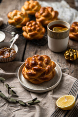 Breakfast with knot buns, orange jam, cream cheese and  black tea with lemon on wooden table. 