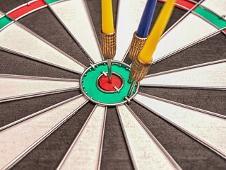 Side view of a dartboard with three darts in the bull's eye. Well-aimed dart throwing. Triple bull's-eye hit. Successful attempts.