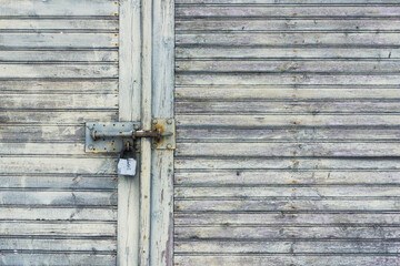 Wooden garage door. Metal padlock background. Peeling paint wood. Vintage rustic gate. Empty copy space grunge door texture.