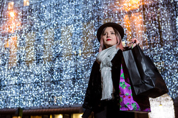 Bella ragazza con i capelli castani dipinti di viola con un cappotto e  un cappello nero  và in...