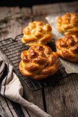 Homemade brioche knot buns on cooling rack on wooden table. 