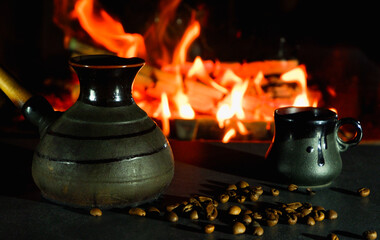 Cezve and coffee cups with coffee beans on the background of a burning fire. Turkish coffee.