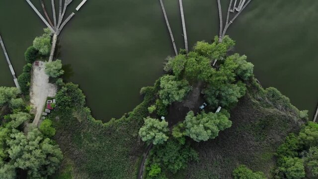 Aerial top down showing forest trees and wooden jetty connected to the cottage holiday houses. Lake Bokod,Hungary.