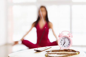Sandalwood incense stick, rosary and alarm clock on the table against the background of a...