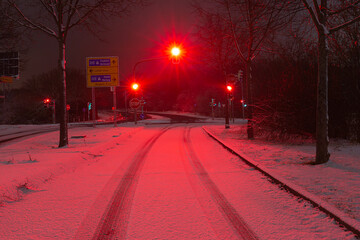 red traffic lights at night on a snow covered road