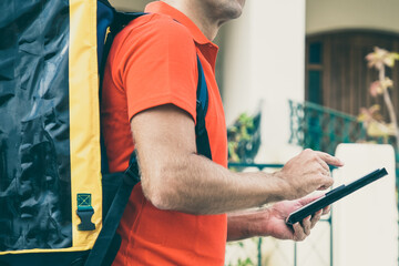 Cropped view of deliveryman looking for house address and holding tablet. Unrecognizable courier...