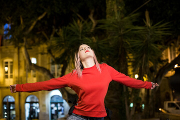 Bella ragazza bionda con maglione rosso  in contesto urbano notturno