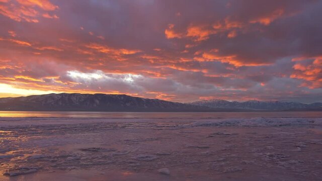 Panning over a frozen lake in winter during sunset in Utah Valley.