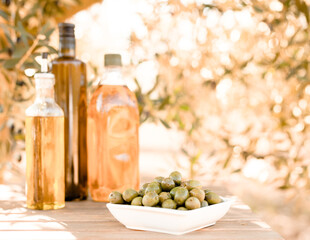 green olives and oil on table in olive grove