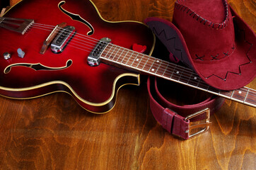 Jazz guitar, cowboy hat and belt on a wooden background.