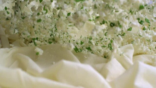 Turkish pastry is being prepared. Pouring feta cheese in slow motion.