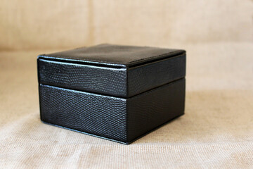 Beautiful closed black leather jewelry box with velvet beige upholstery close up